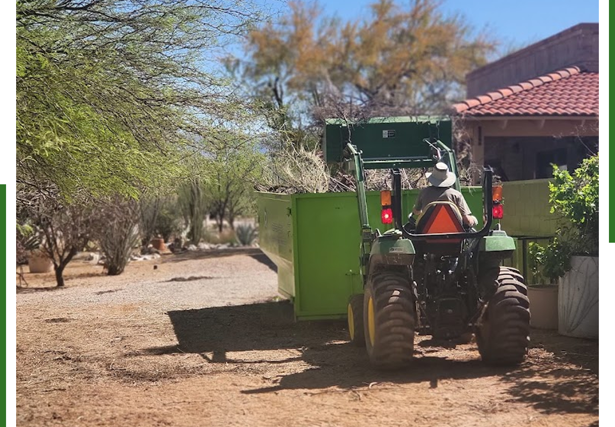 Tractor moving green container near house.